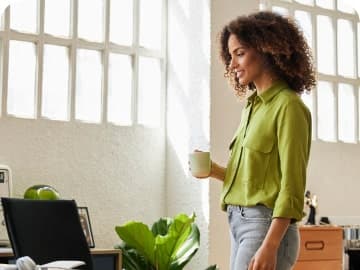 Woman holding a mug, walking back to her desk