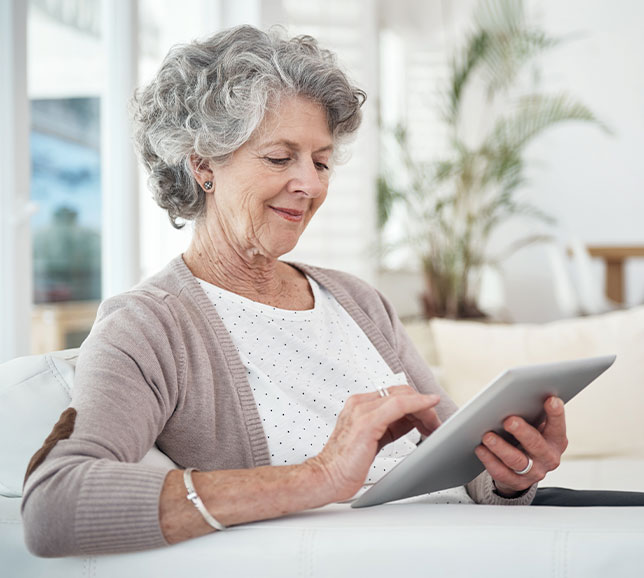 Senior woman sat on a sofa using a tablet device