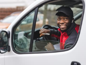 Smiling delivery driver looking out through the window of his car