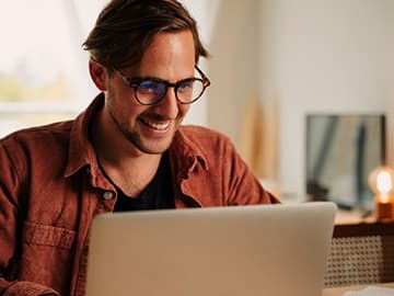 Student with glasses on working on laptop