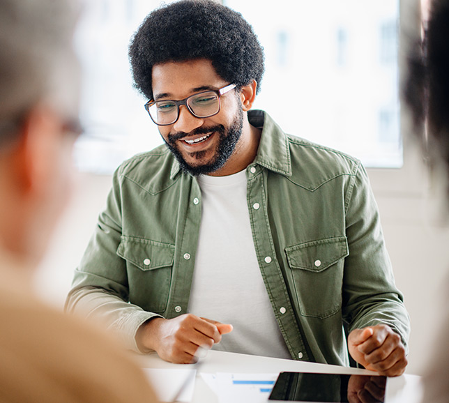 Man wearing glasses and working at a desk with colleague