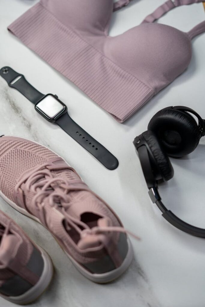 Flat lay of gym essentials with pink sportswear and smartwatch.